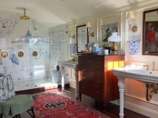 A spacious bathroom with a black clawfoot tub, floral curtains, a Persian-style rug, and a large white sink.  | BRG